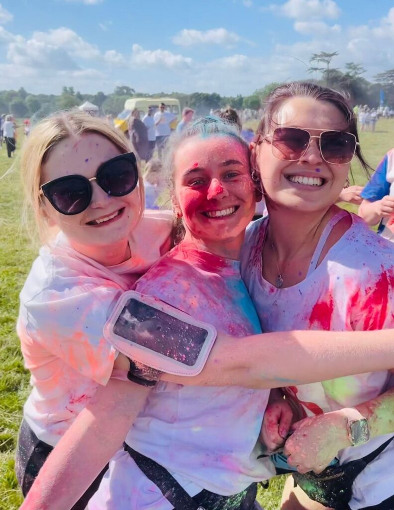 3 ladies post run covered in coloured paint.