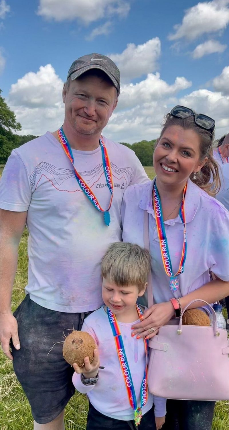 Family of 3 smiling and wearing medals.