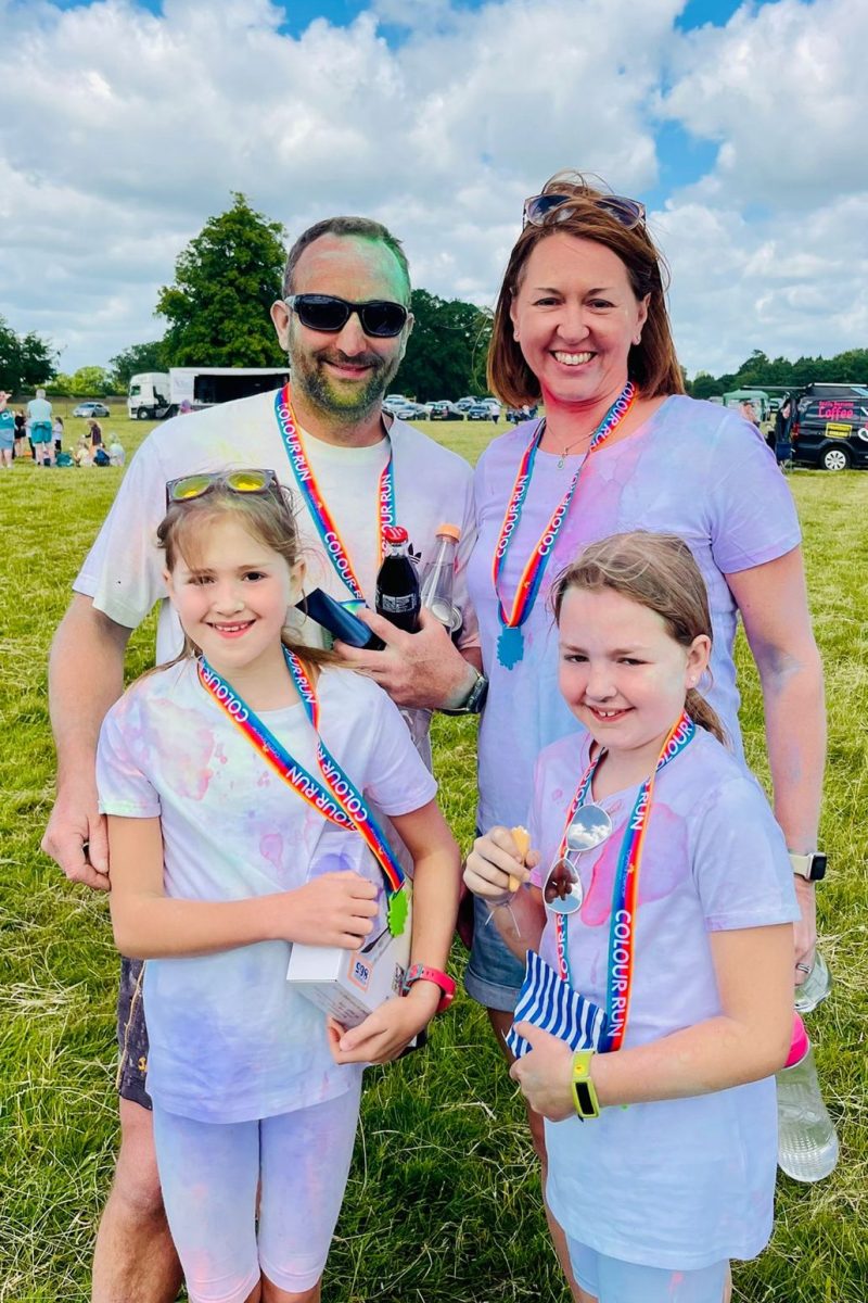 Family of 4 smiling with medals.